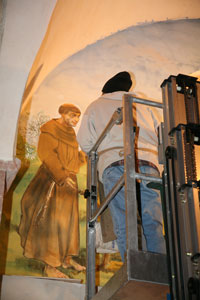 M. Callossi mentre ritocca l'affresco di S. Francesco ed il Lupo