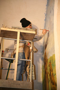M. Callossi mentre ritocca l'affresco di S. Francesco ed il Lupo